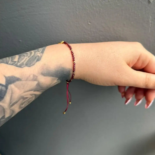Red beaded crystal gemstone bracelet with gold accents, heart charm, adjustable string