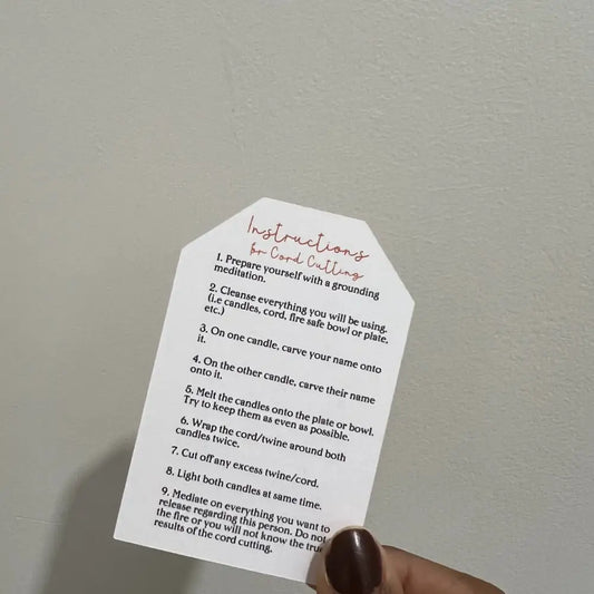 Hand holding white octagonal Cord Cutting Ritual Candle card with black text and pink accents