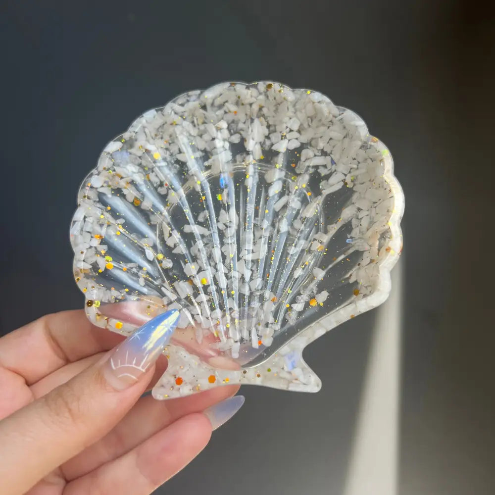Clear scallop shell trinket dish with glitter and embedded shells in resin
