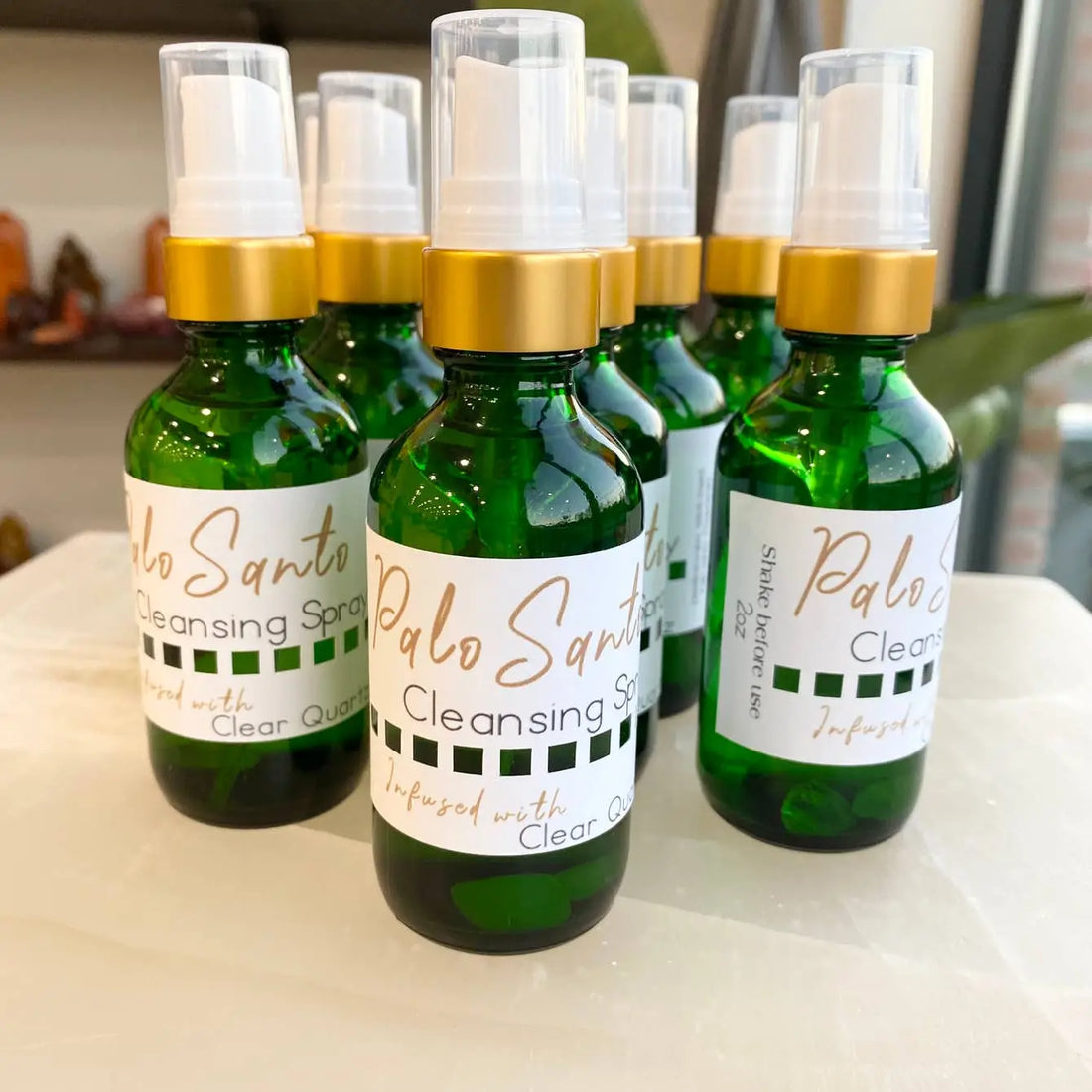 Palo Santo cleansing spray with clear quartz in green bottle and gold cap