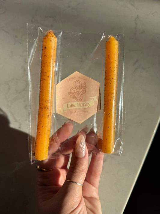 Two honey orange taper candles in a clear sleeve with a Like Honey Ritual Candle label