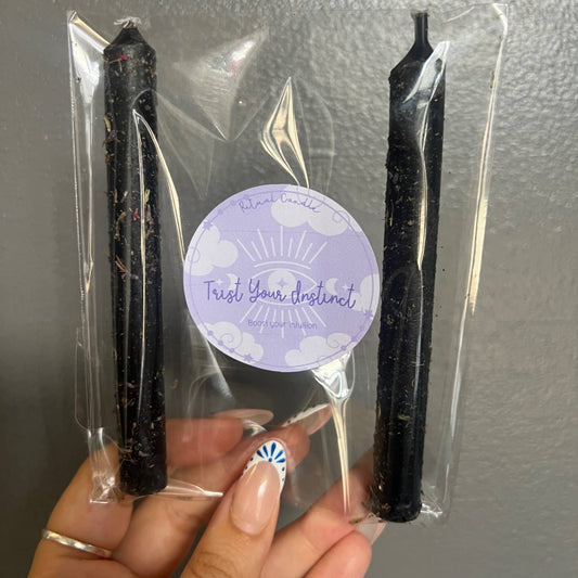 Two black taper candles in a clear sleeve with a Trust Your Instinct Ritual Candle label
