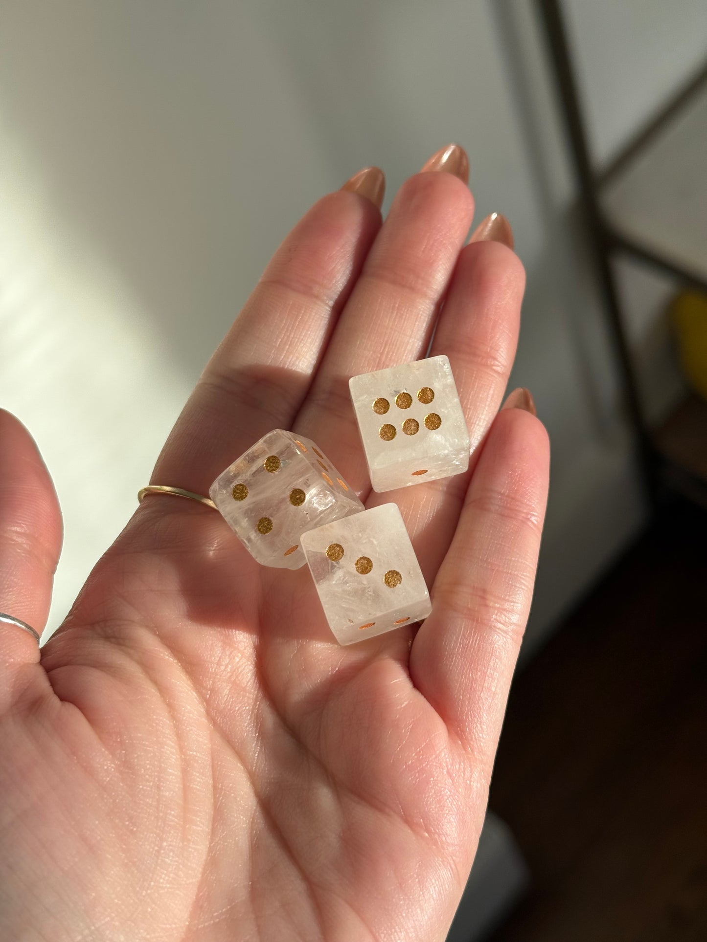 Three clear crystal dice with gold dots are held in a hand.