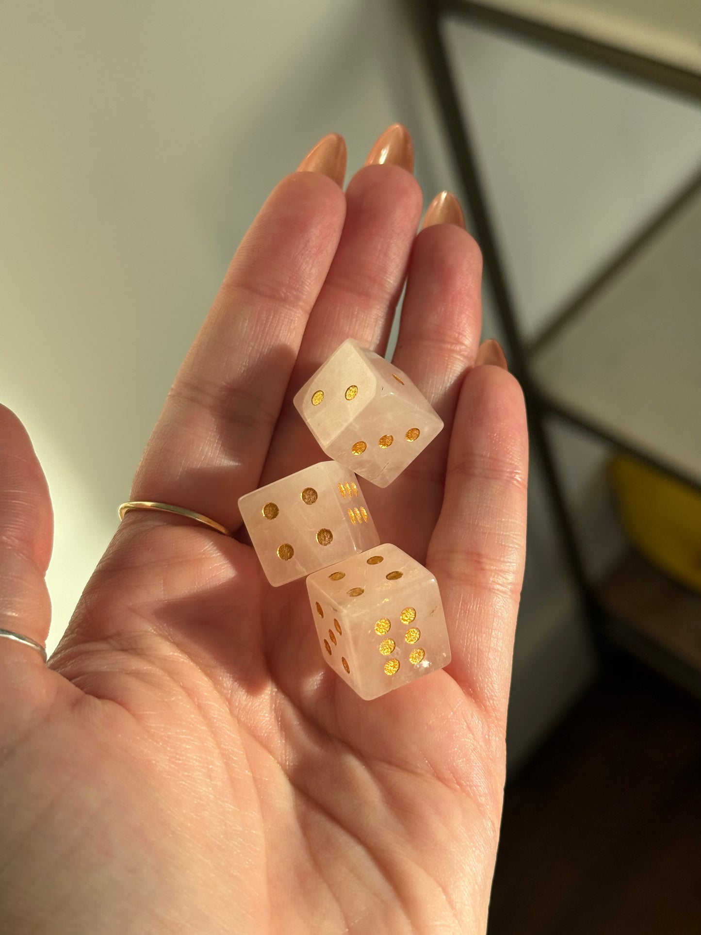 Three translucent crystal dice with gold pips are held in a hand.