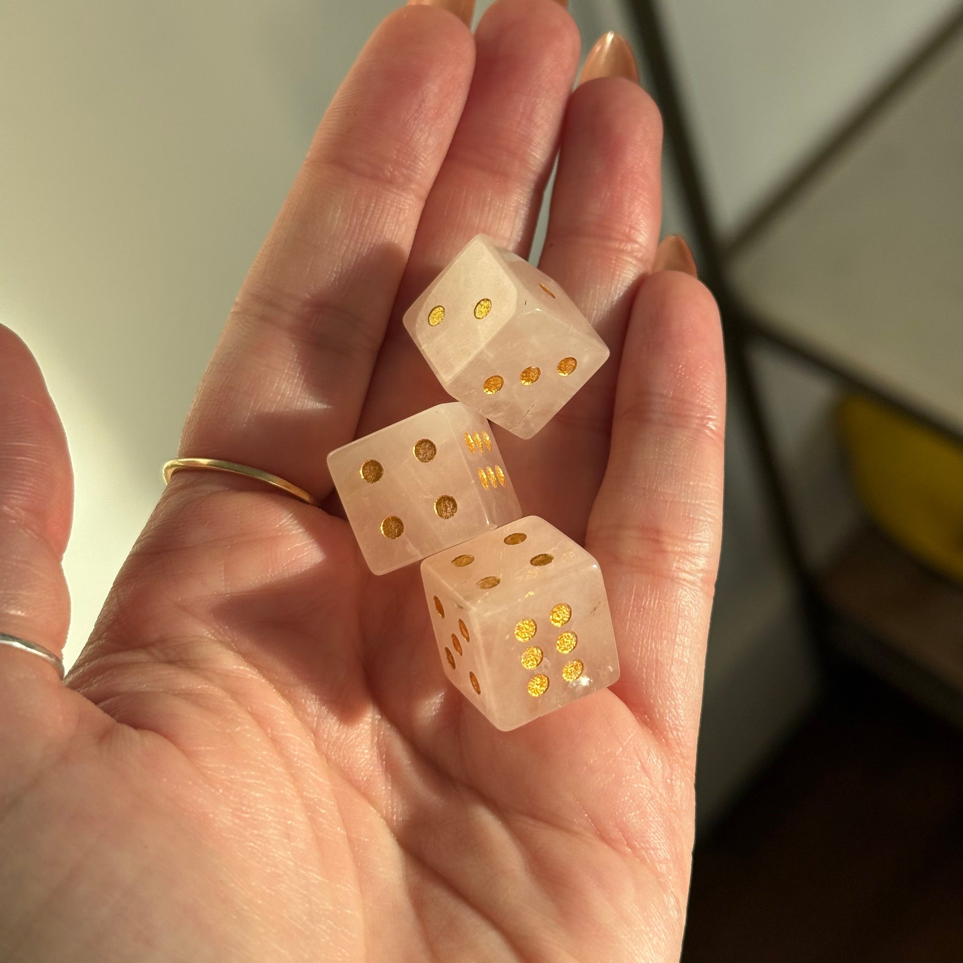 Three translucent crystal dice with gold pips are held in a hand.