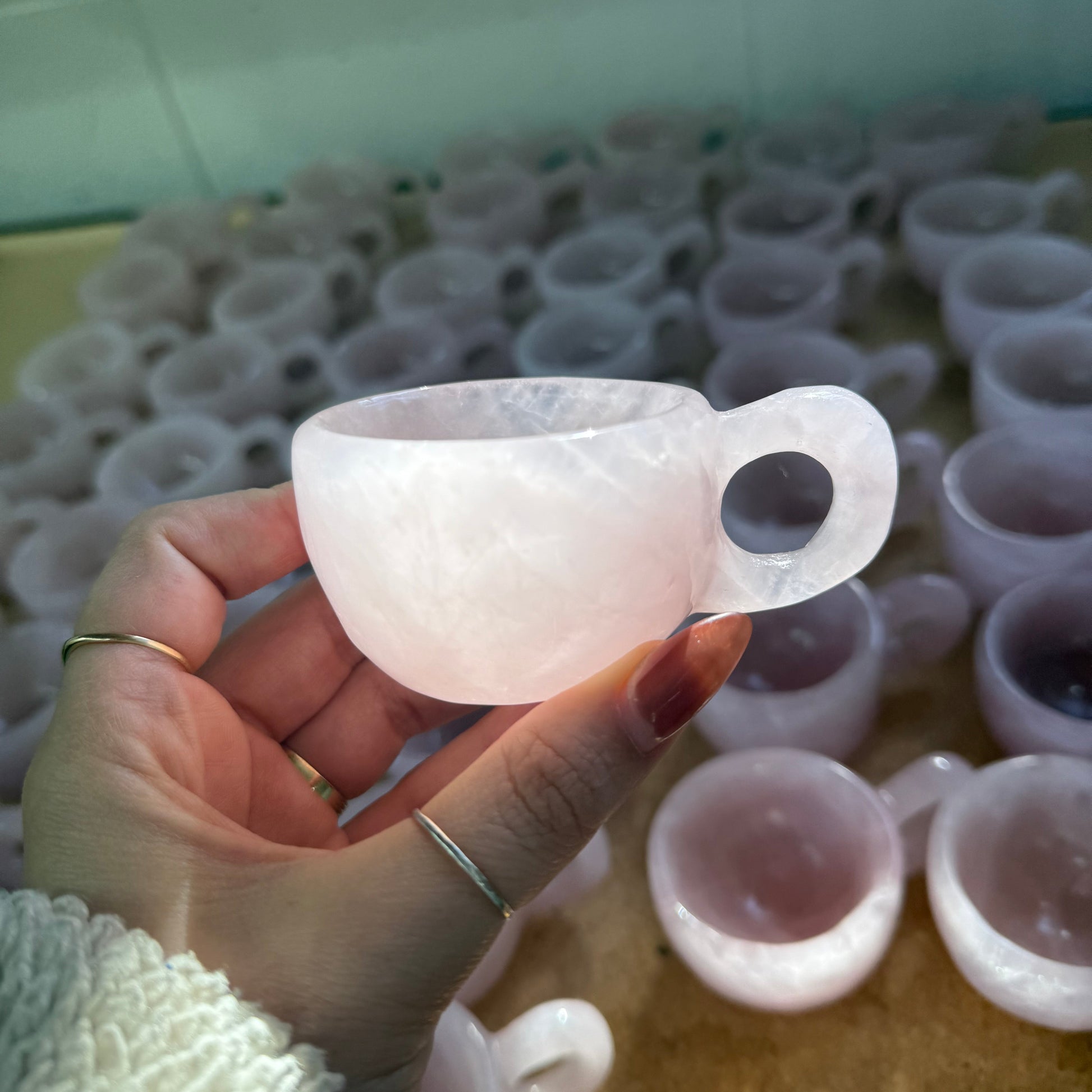 Hand holding a white silicone ring with a blurred background of similar rings.