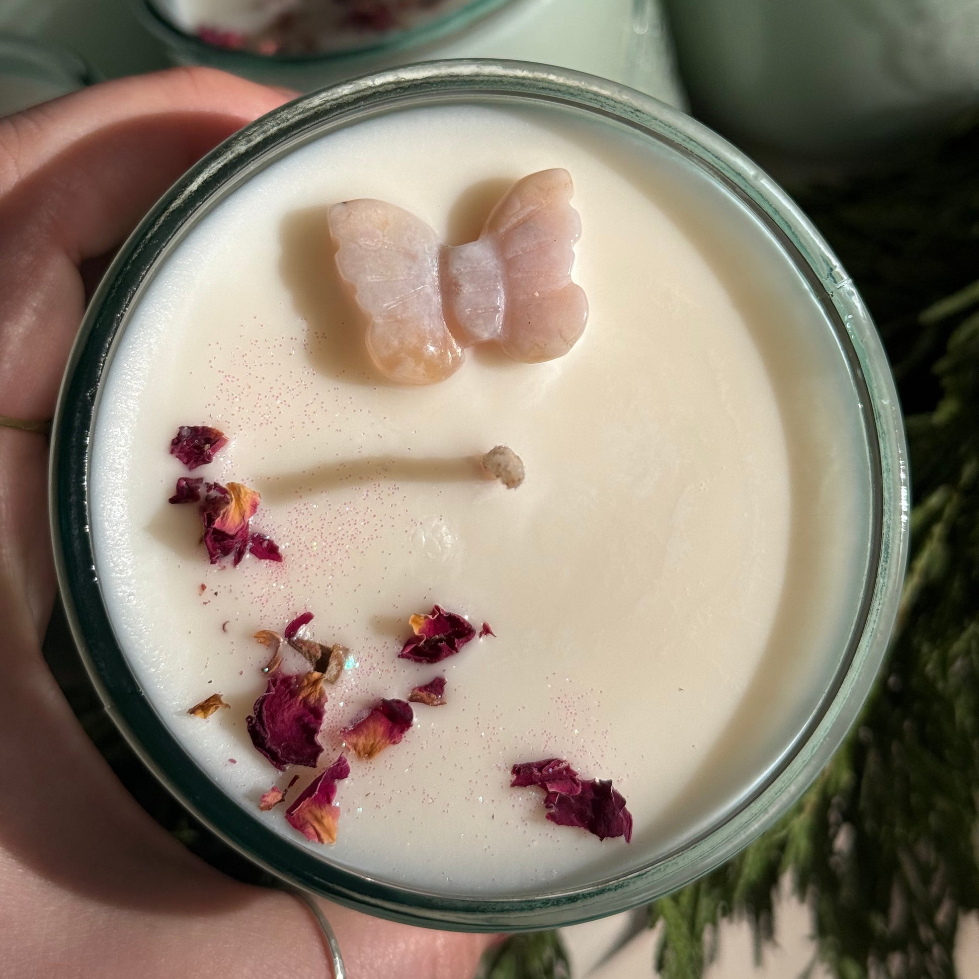 Candle with butterfly and flower decorations held by a hand