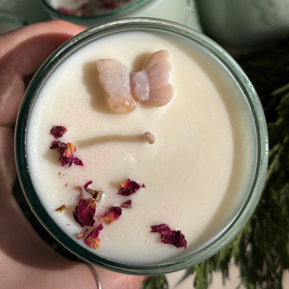 Candle with butterfly and flower decorations held by a hand