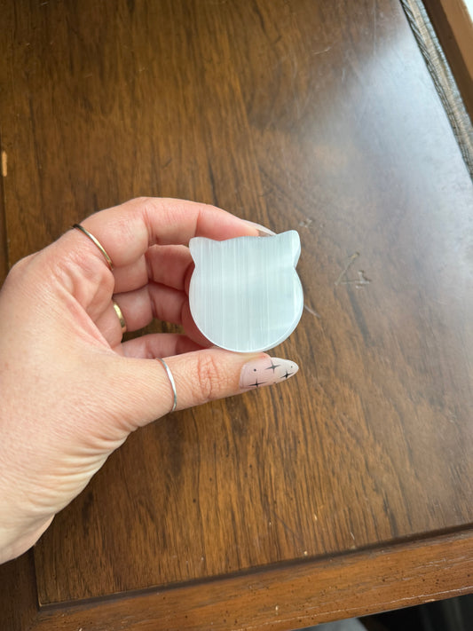 Polished selenite cat-shaped bowl on a wood surface