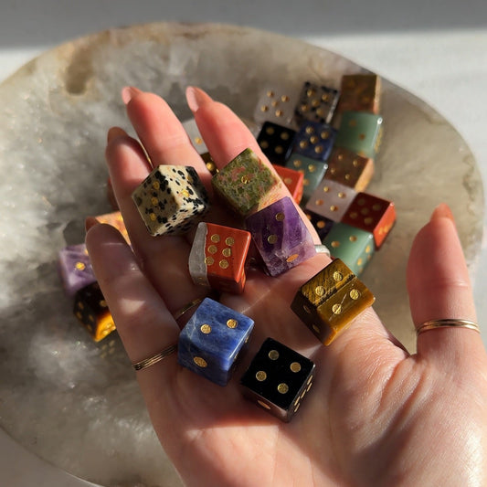Hand holding colorful dice with a stone surface background