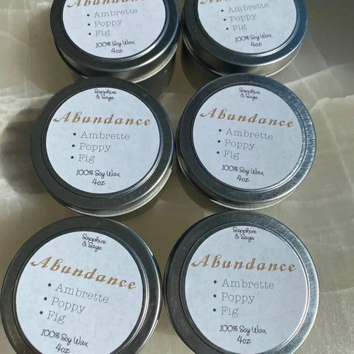 4oz soy candle in silver tin with abundance label, ambrette poppy fig scents, citrine crystals
