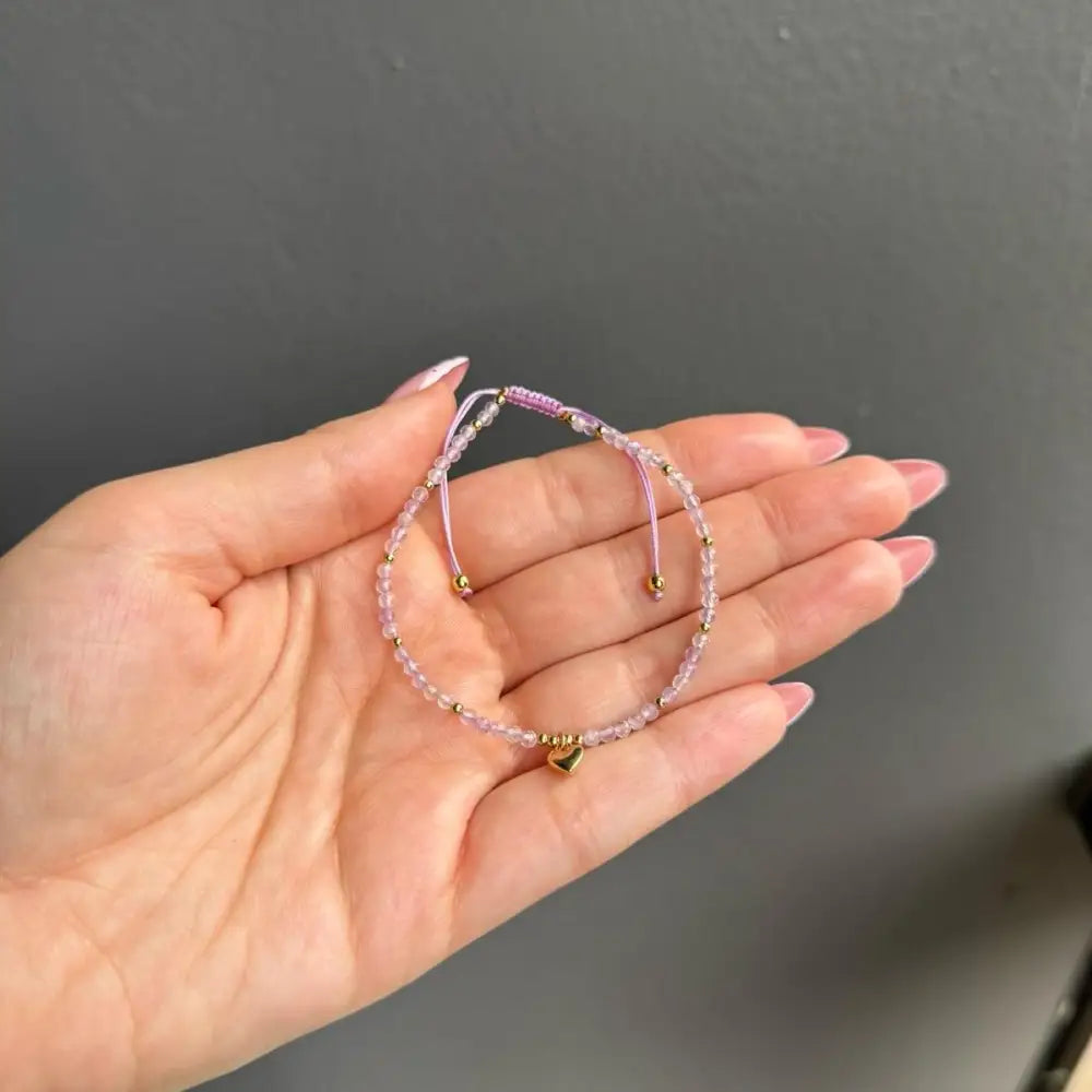 Lavender beaded adjustable bracelet with gold accents, heart charm, and bell