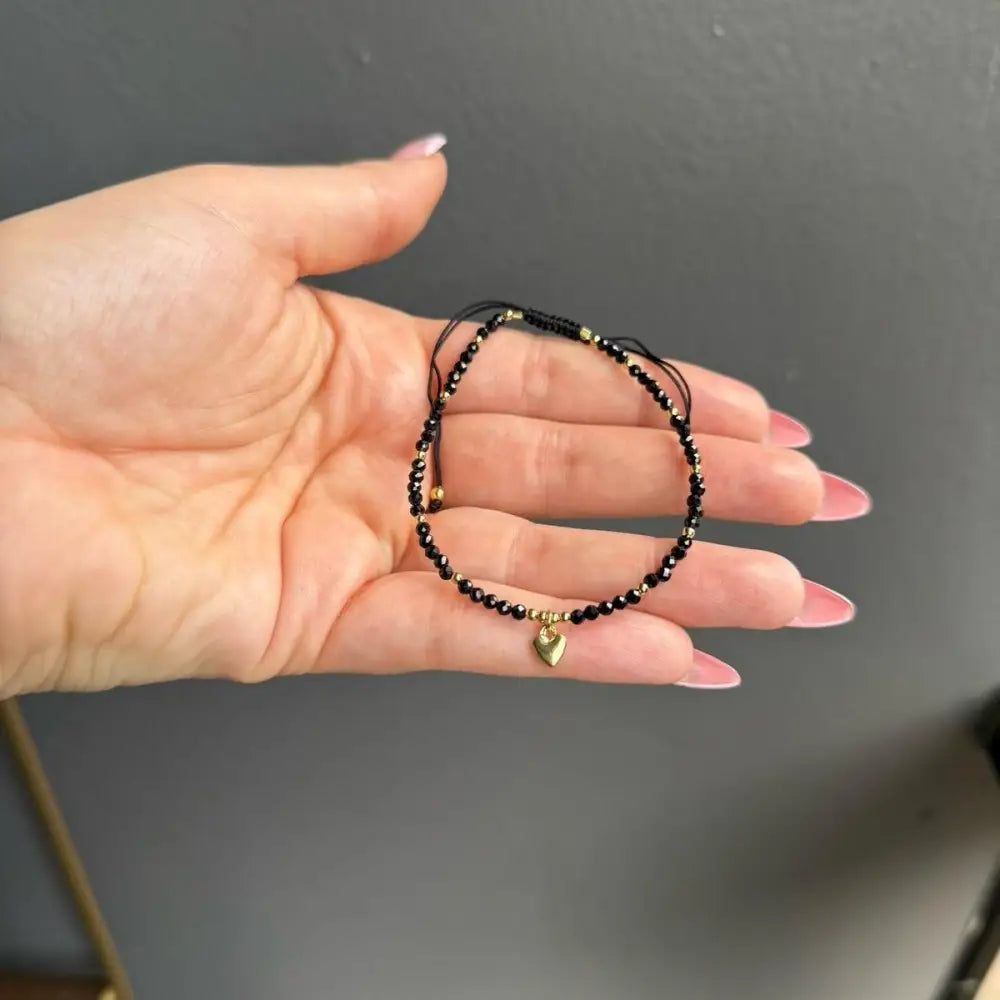 Handmade black beaded adjustable bracelet with gold accents and heart charm