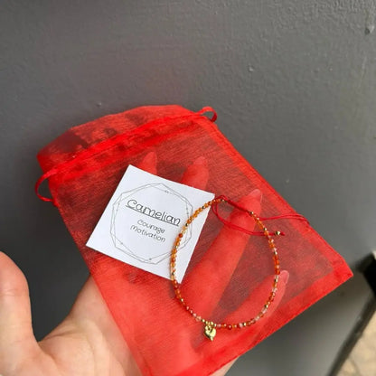 Red beaded adjustable crystal gemstone bracelet with gold heart charm in organza bag