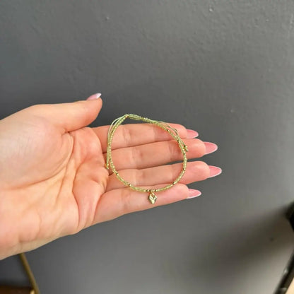 Gold heart charm bracelet with woven texture and adjustable crystal gems