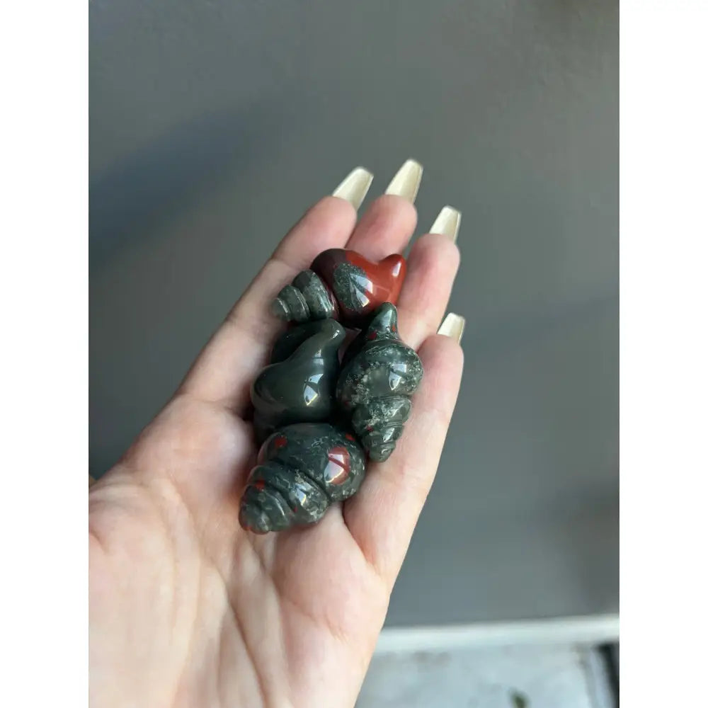 Hand holding green and red polished stone beads in 1 Inch Calming Crystal Carving for Tranquility