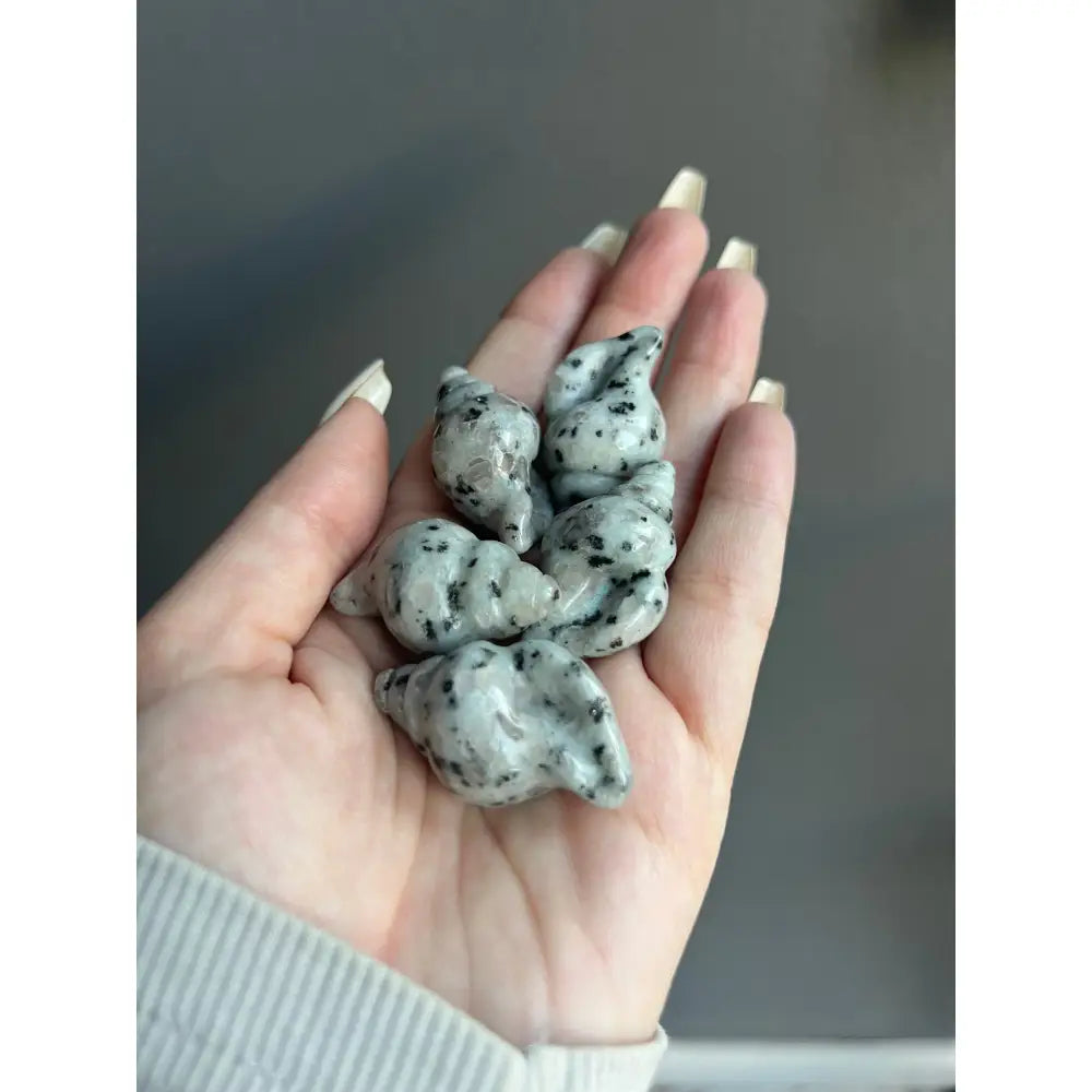 Hand holding white and black speckled 1 inch calming crystal carving for tranquility