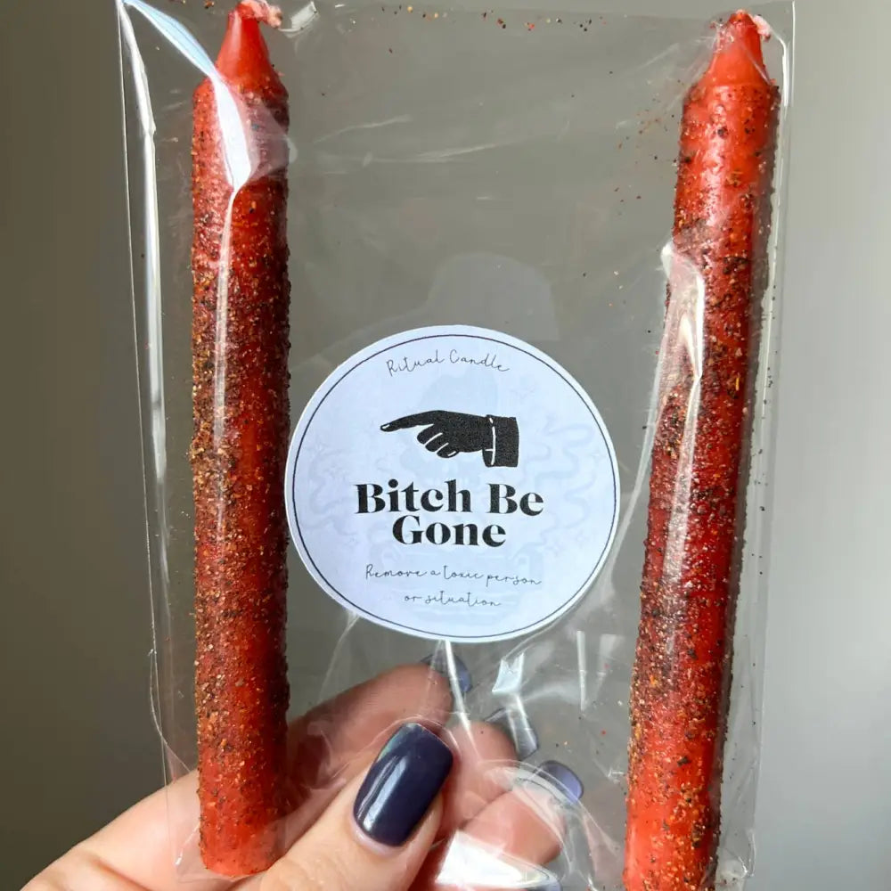Red glittery Bitch be Gone ritual candle in clear packaging with hand graphic