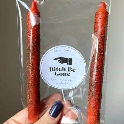 Red glittery Bitch be Gone ritual candle in clear packaging with hand graphic