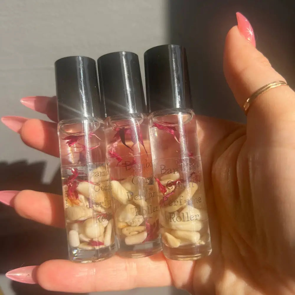 Clear glass Cedar Wood and Pear perfume roller bottles with black caps and floral accents