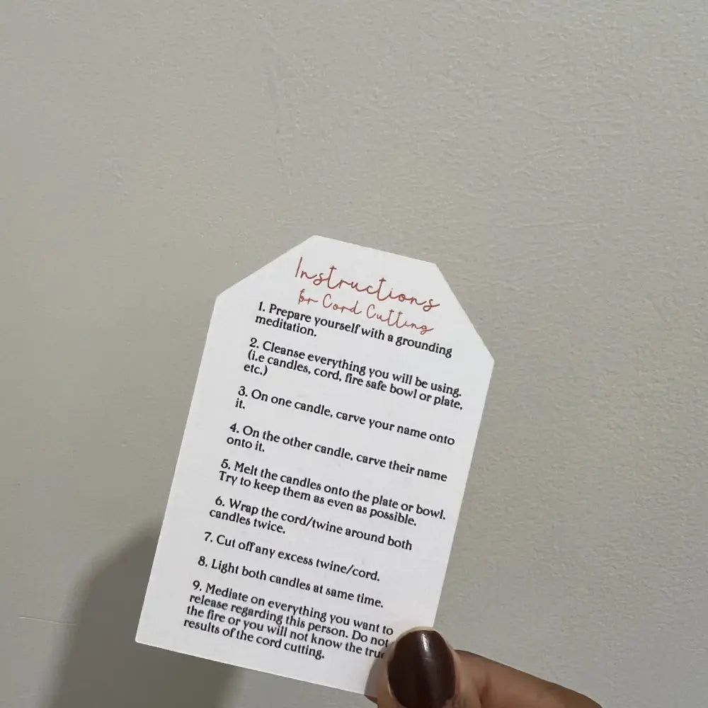 Hand holding white octagonal Cord Cutting Ritual Candle card with black text and pink accents
