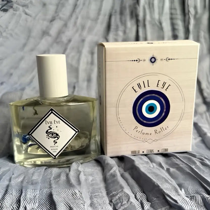 Clear glass evil eye perfume roller bottle with white cap and botanicals