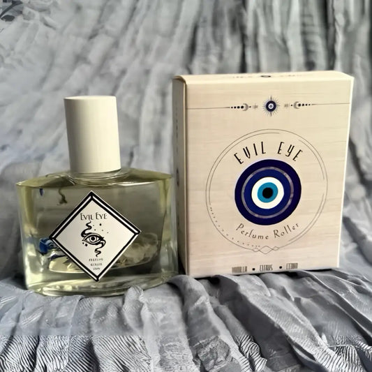 Clear glass evil eye perfume roller bottle with white cap and botanicals