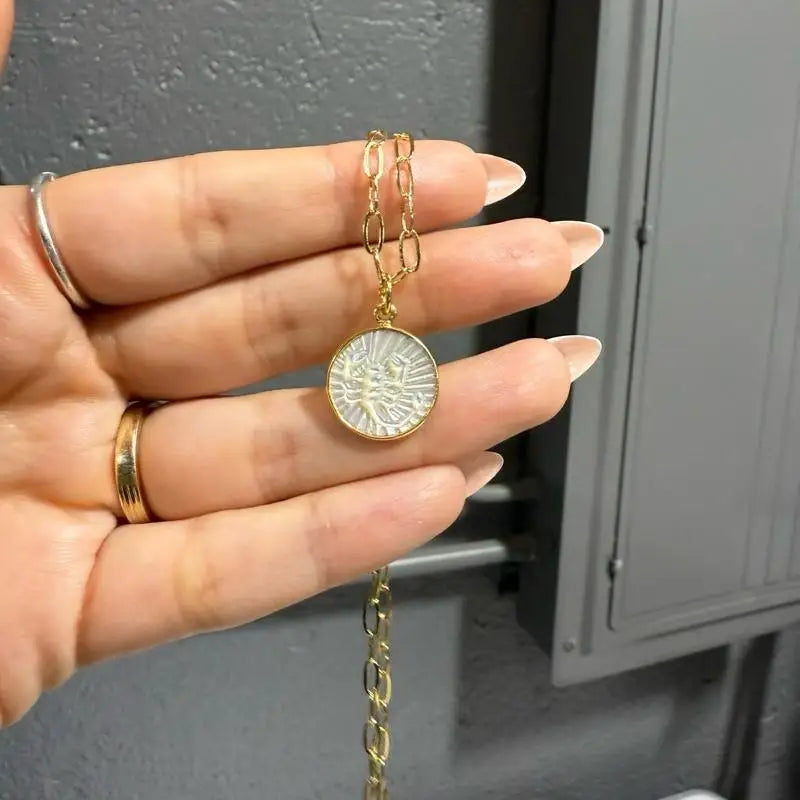 15mm gold zodiac pendant necklace with intricate design and white stone center