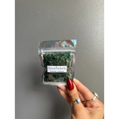 Premium crystal chip stones with green tarragon herb in clear plastic packaging, red nail polish, and silver rings for crafts and home decor