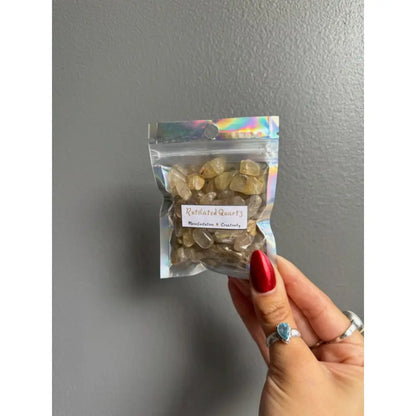 Clear plastic bag of raw calcite crystal chips with red nail polish and silver ring for crafts