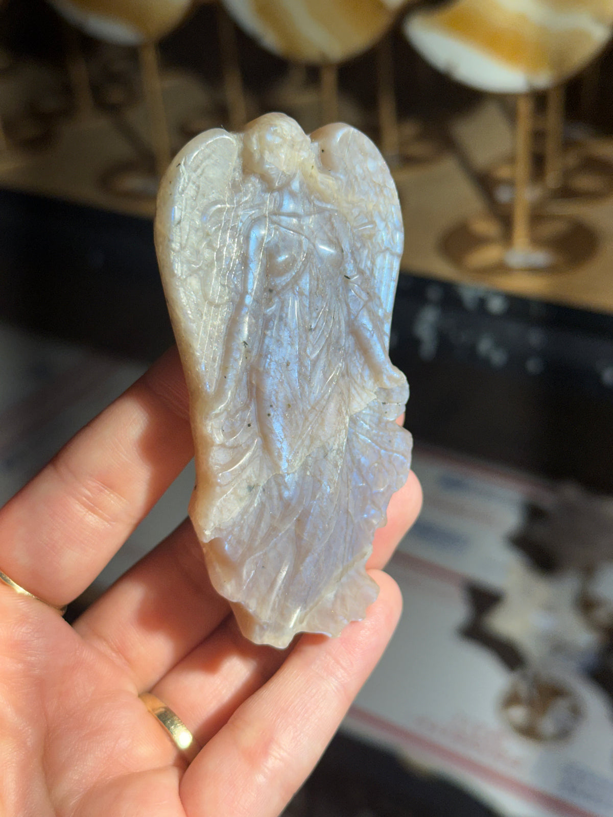 Moonstone angel carving held in hand showing blue flash across the wings and gown