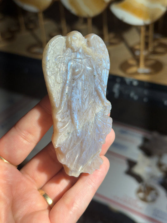 Moonstone angel carving held in hand showing blue flash across the wings and gown