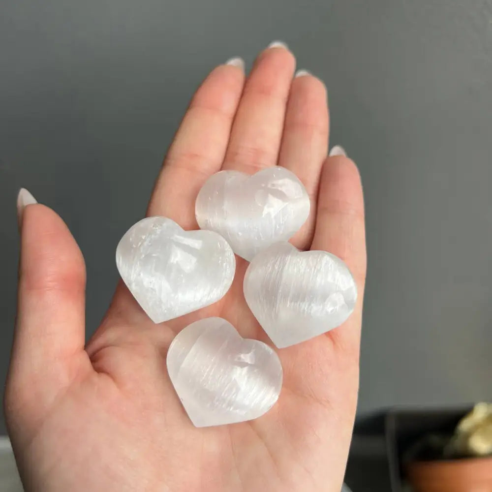 Hand holding natural Moroccan selenite heart carving, half inch size