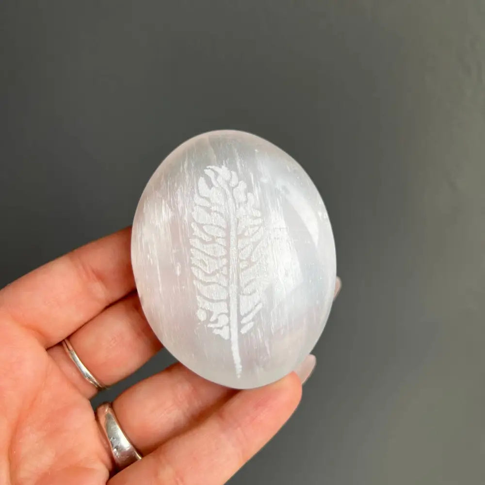 White Moroccan selenite egg with leaf design in silver-ringed hand