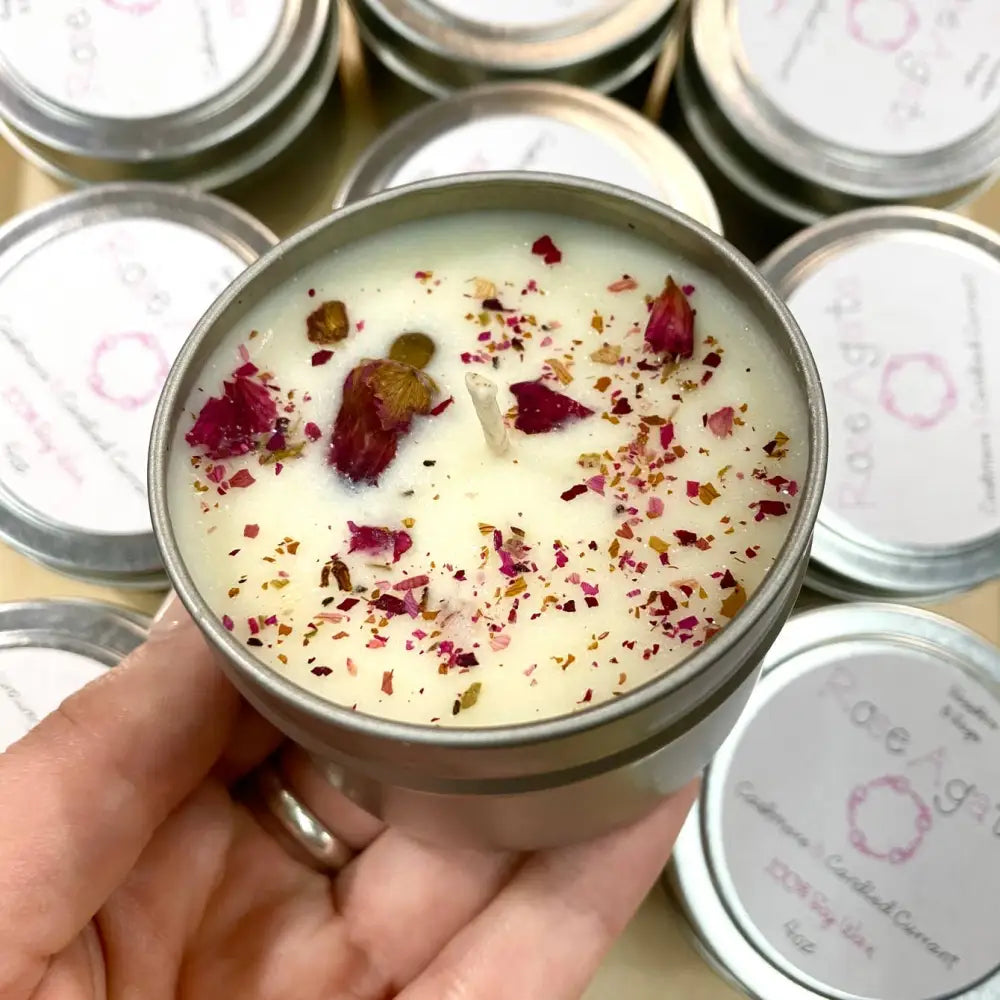 Hand holding cream soy Rose Agate Tin Candle with dried roses and leaves, 4oz