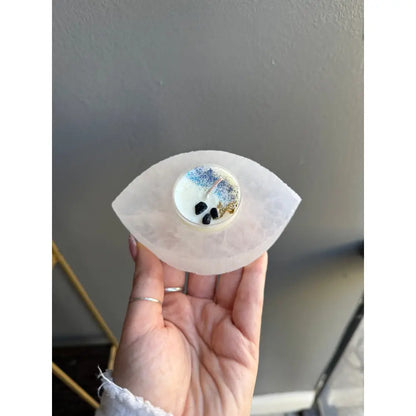 White eye-shaped soap bar with black speckles, blue swirls in Selenite Candle Holder