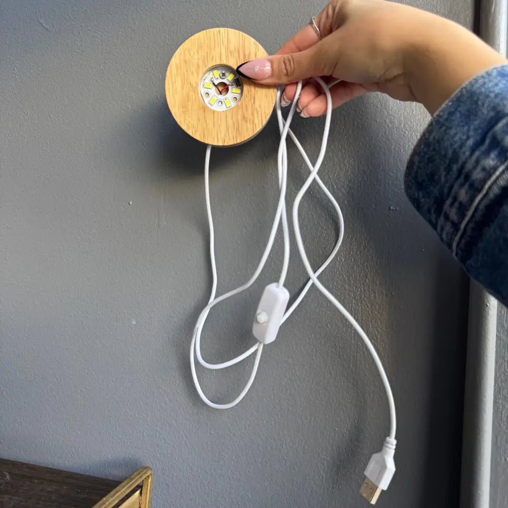 Light brown wooden disc wall charger with white cord and USB port