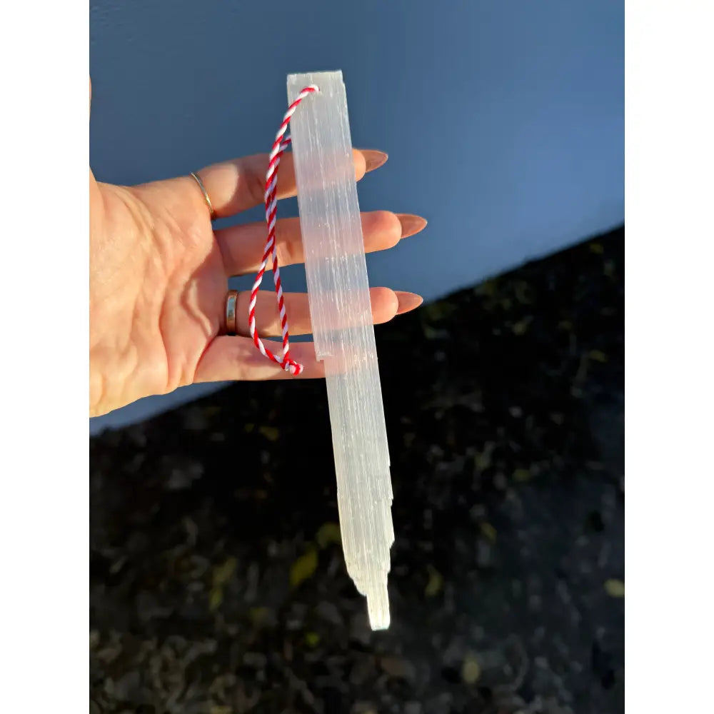 White selenite wand with red white string handle ornament