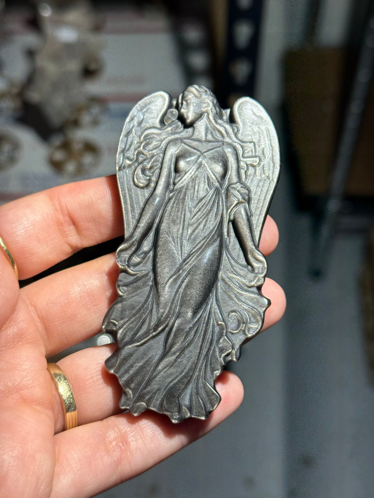 Silver sheen obsidian angel carving held in hand showing the grey silver sheen across the wings and gown