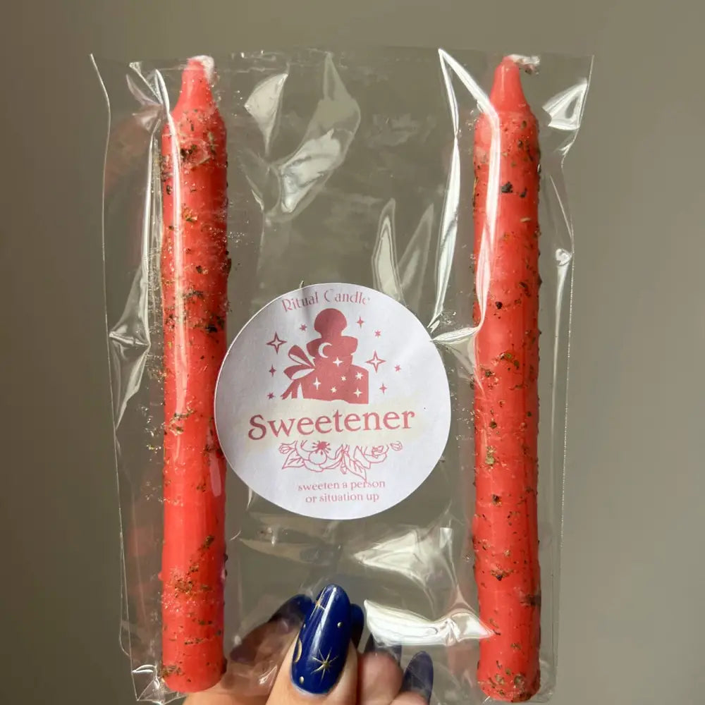Red speckled taper candles in clear pack labeled Sweetener, 2-pack ritual with herbs and oils