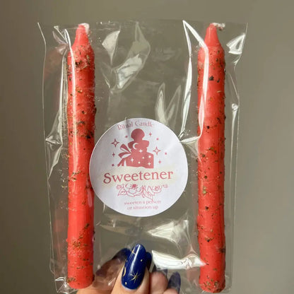 Red speckled taper candles in clear pack labeled Sweetener, 2-pack ritual with herbs and oils