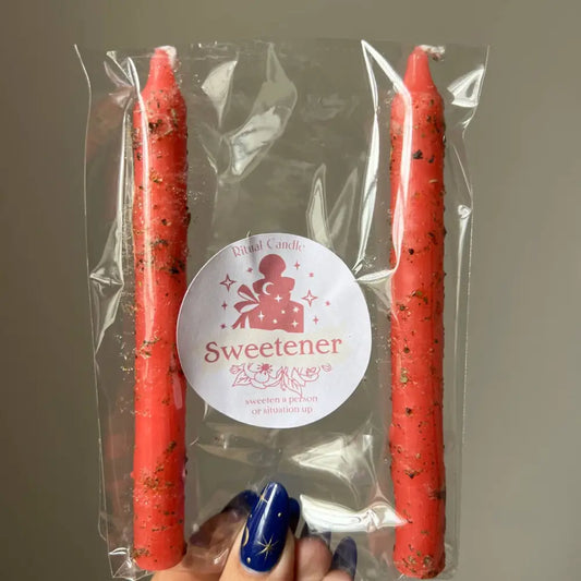 Red speckled taper candles in clear pack labeled Sweetener, 2-pack ritual with herbs and oils