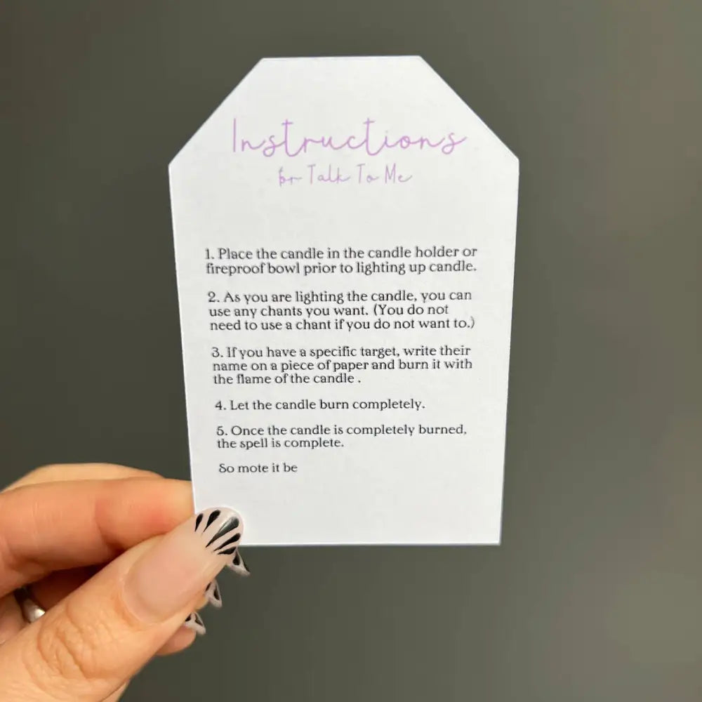 White paper tag with purple text and black nail polish for Talk to Me Ritual Candles