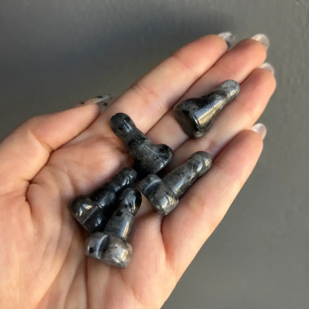 Black textured rubber earplugs on natural stone crystal phallus carving